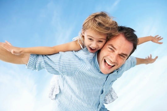 Father giving piggyback ride to daughter with arms outstretched